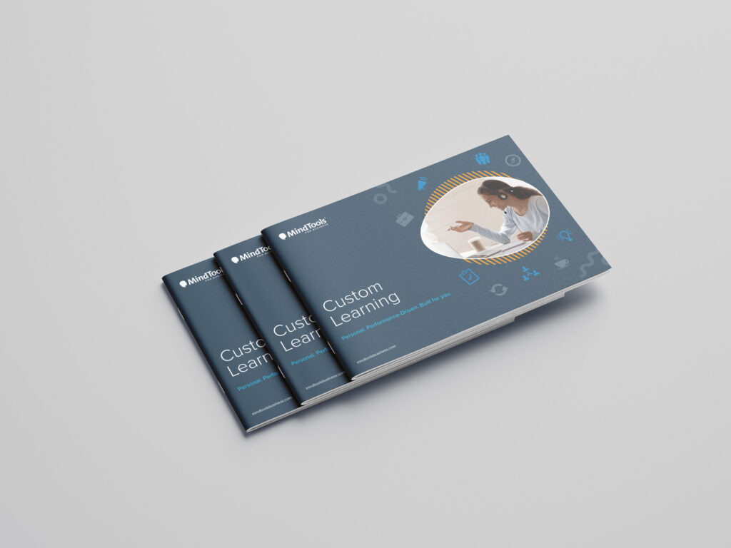 MindTools custom learning brochure — fanned stack of navy printed booklets with circular portrait photograph