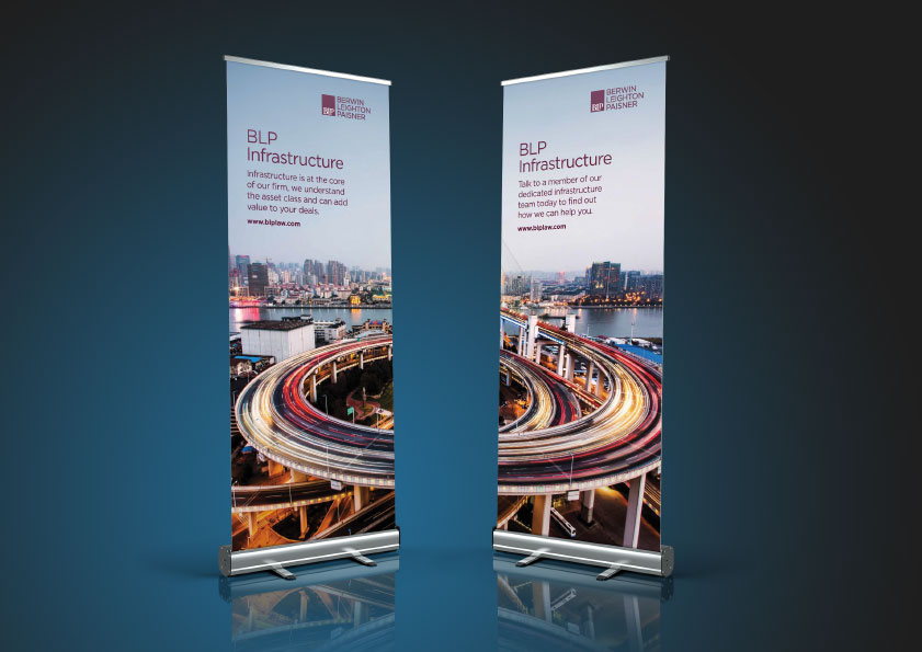 BCLP Law infrastructure practice roller banners — pair of pull-up exhibition stands against dark teal studio background